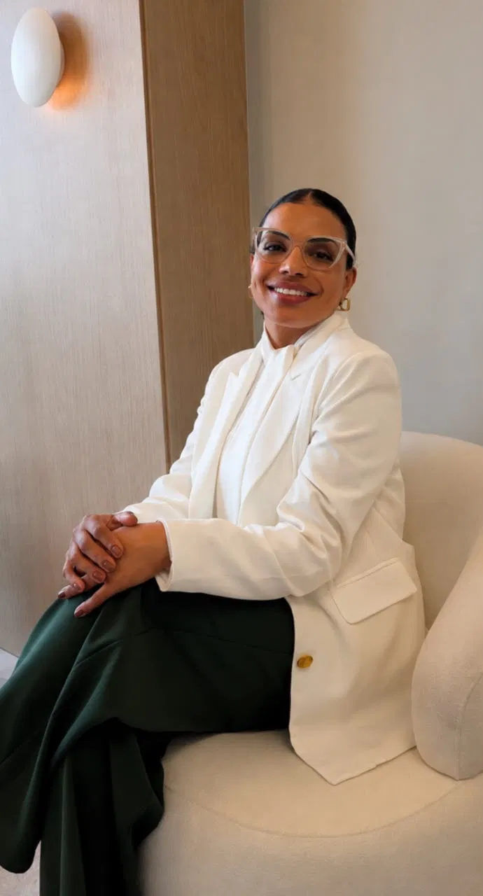 Fabiana Fiume de blazer branco sentada em poltrona no consultório